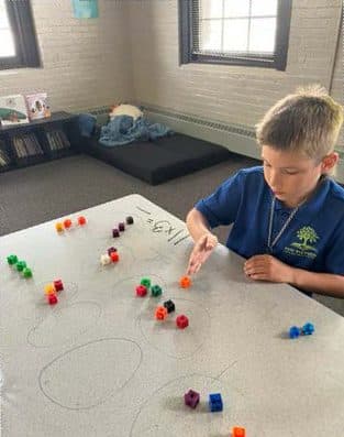 A New Richmond Prep student arranging colorful cubes on a classroom table.