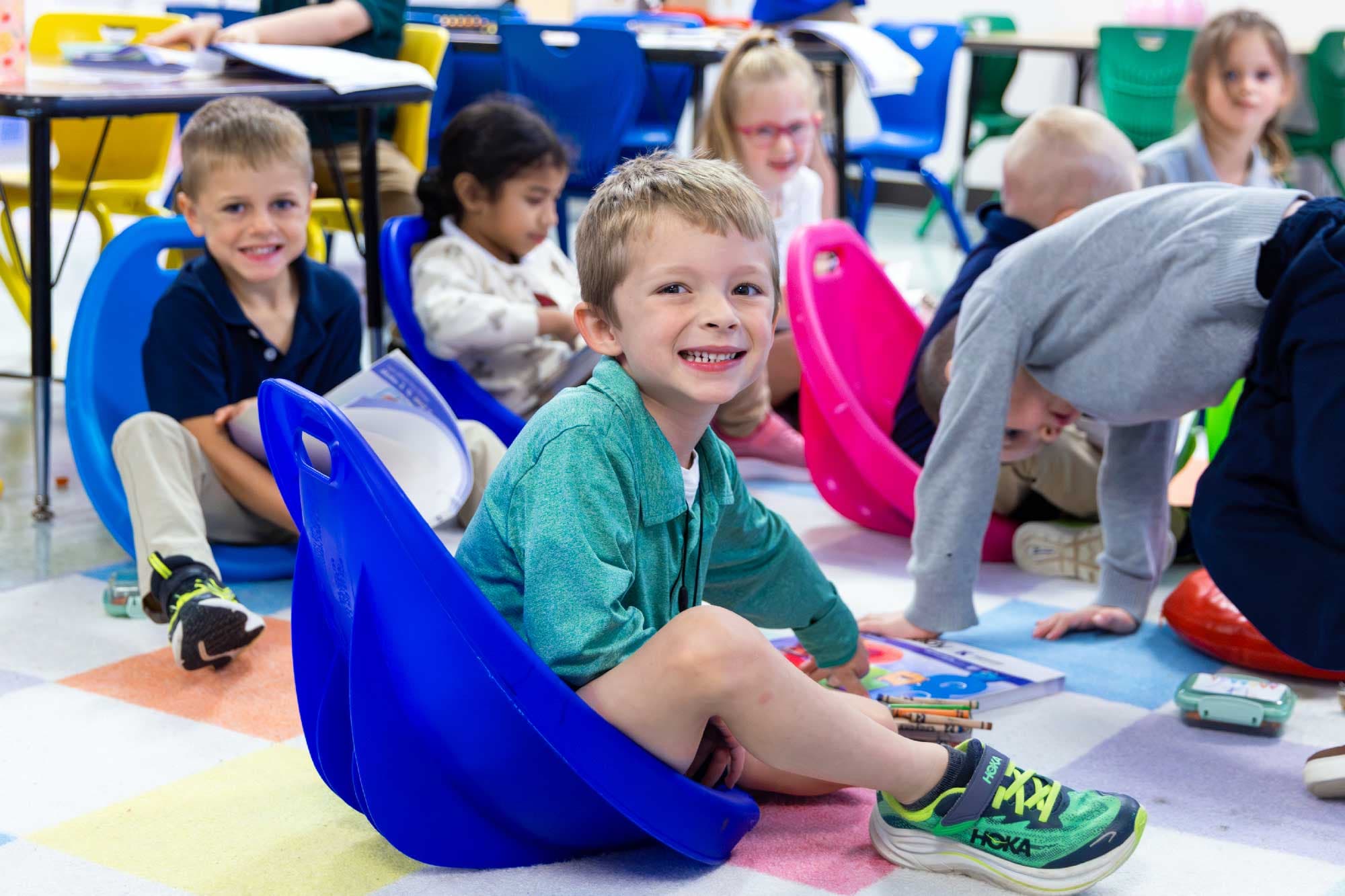 Young students sitting on colorful floor seats during a classroom lesson.